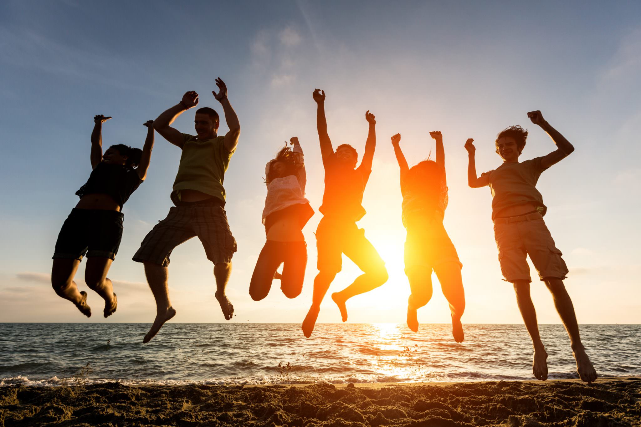 Saut groupé devant la mer au coucher du soleil