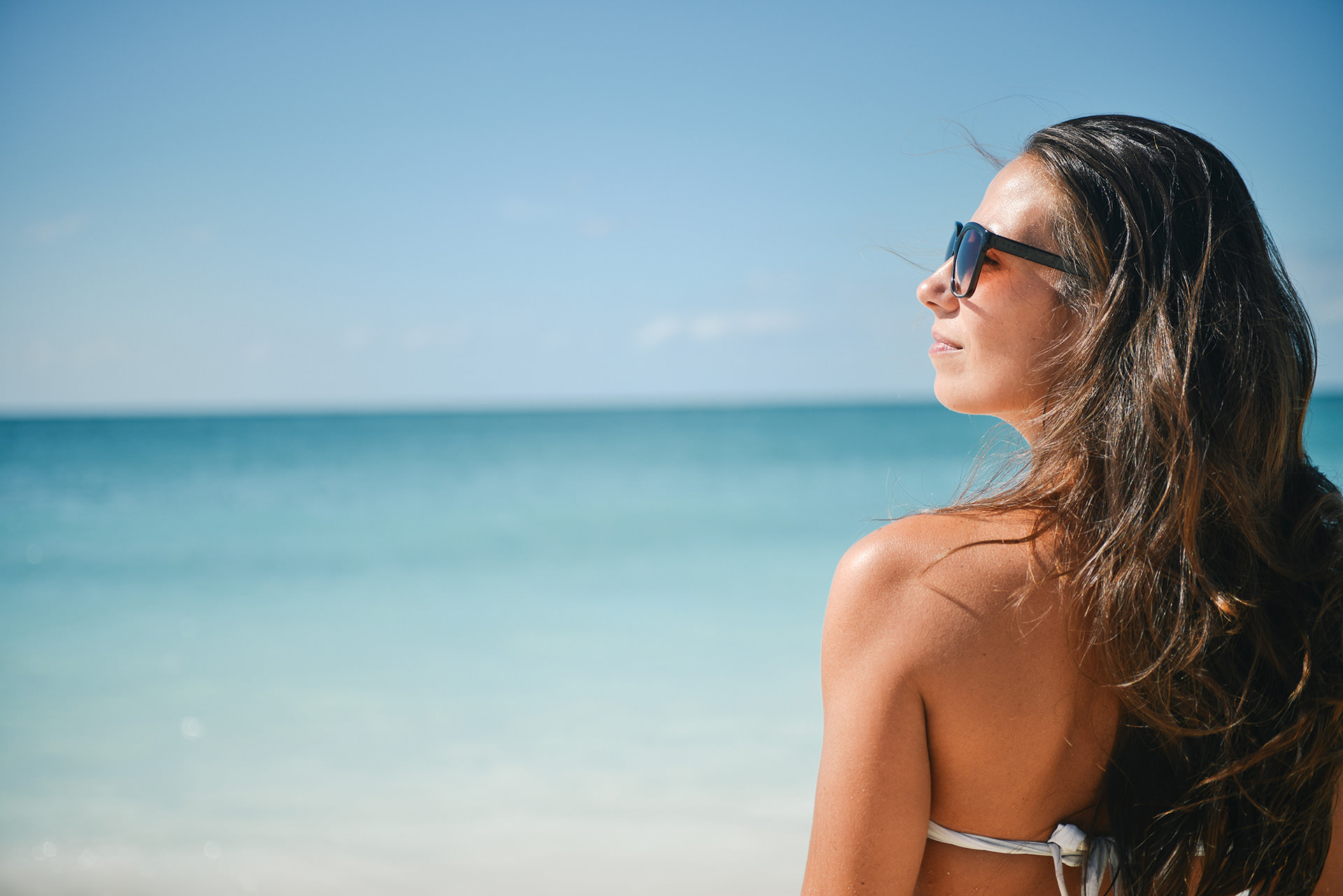 Femme avec lunette de soleil devant océan